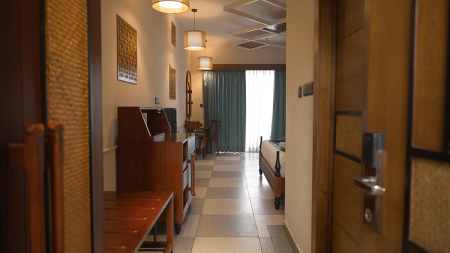  A view from the entrance of a guest room showing the wardrobe, refreshment station, and bed area at Hotel Sonar Bangla, Mayapur.