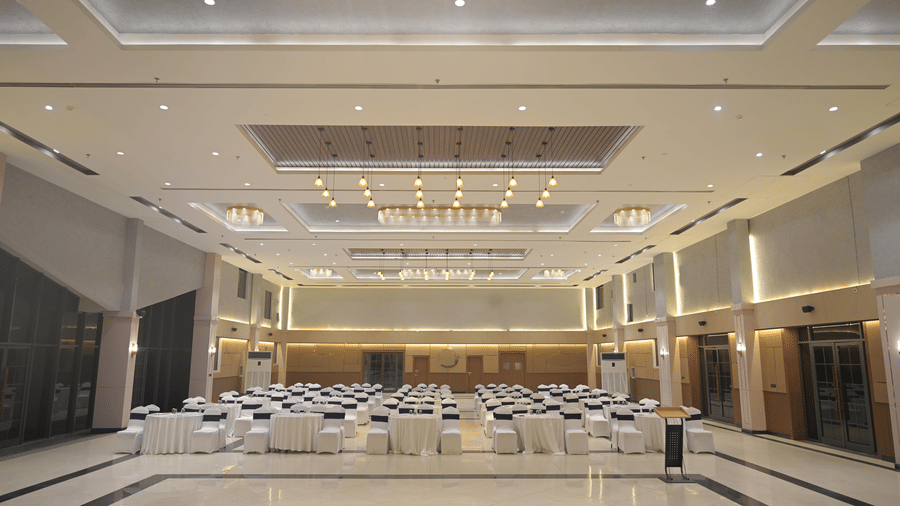 A wide shot of the banquet hall showcasing chandeliers, clean flooring, and event-ready seating at Hotel Sonar Bangla, Mayapur.
