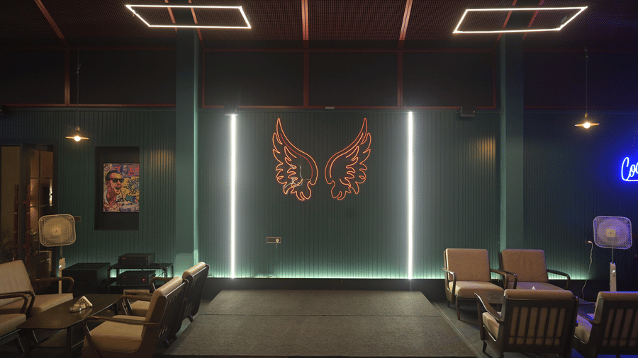 Front-facing view of the lounge bar with a lit butterfly artwork and comfortable seating arranged neatly at Hotel Sonar Bangla, Mayapur.