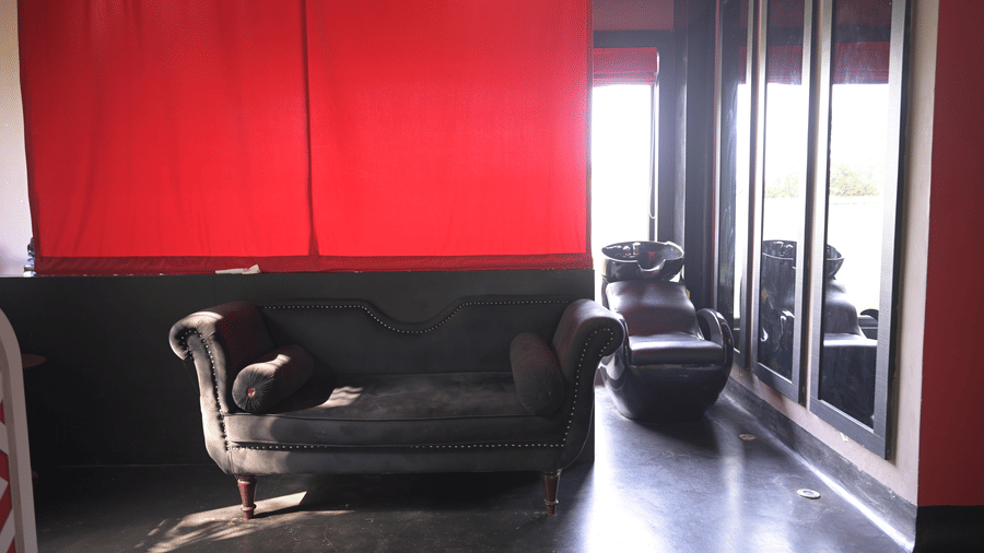 A relaxation lounge with curtains, dark flooring, and comfortable seating at Hotel Sonar Bangla, Mayapur.