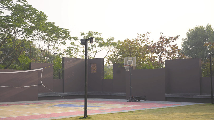 An outdoor basketball court with a single hoop at Hotel Sonar Bangla, Mayapur.