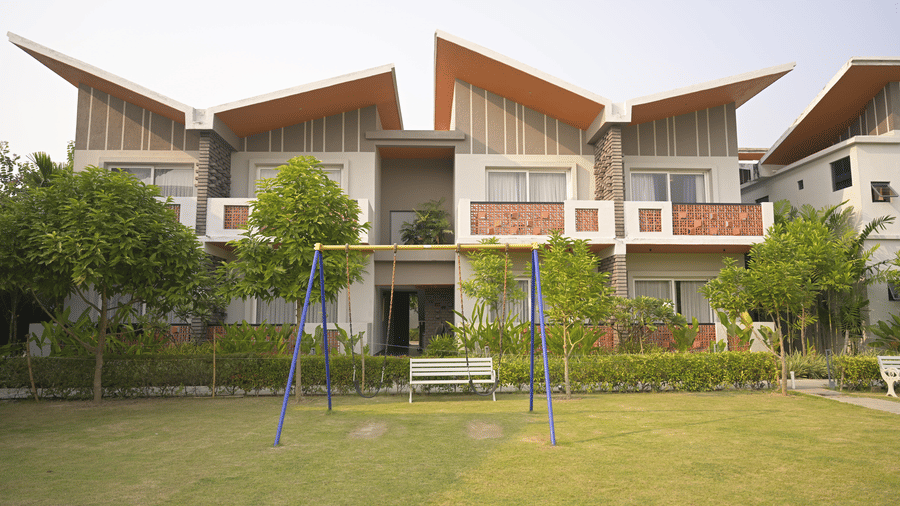 A wide view of the outdoor children’s playground with swings and a lawn in front of the Hotel Sonar Bangla, Mayapur.