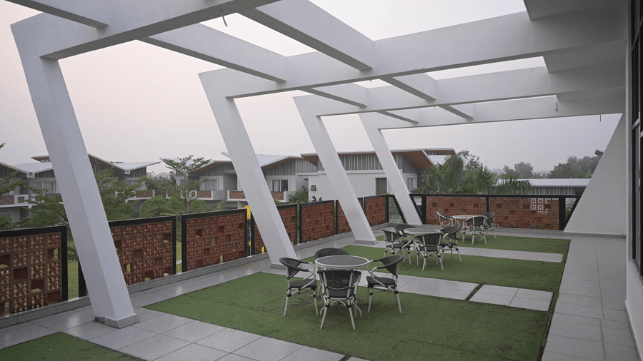 Rooftop seating with architectural beams and garden-style flooring at Hotel Sonar Bangla, Mayapur.