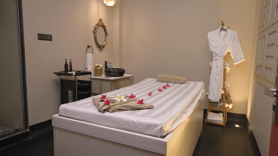 A spa room with a neatly arranged massage bed and treatment essentials at Hotel Sonar Bangla, Mayapur.