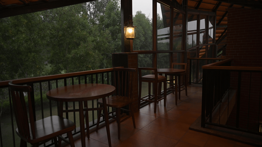 A balcony terrace with wooden furniture and a railing overlooking a forested area at Hotel Sonar Bangla, Sundarban.