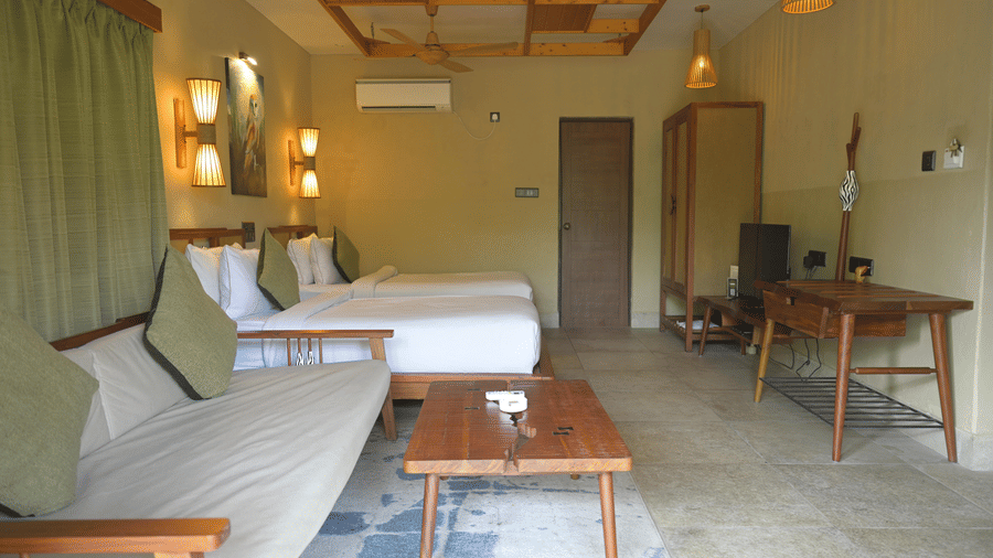 Wide interior view of a hotel room featuring a sofa, coffee table, and twin beds at Hotel Sonar Bangla, Sundarban.
