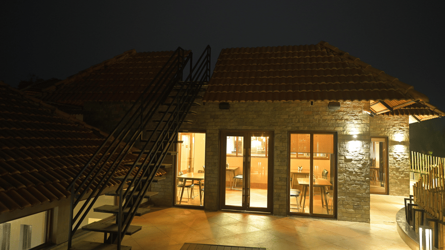 Night view of a stone building exterior with glass doors and a tiled roof at Hotel Sonar Bangla, Sundarban.
