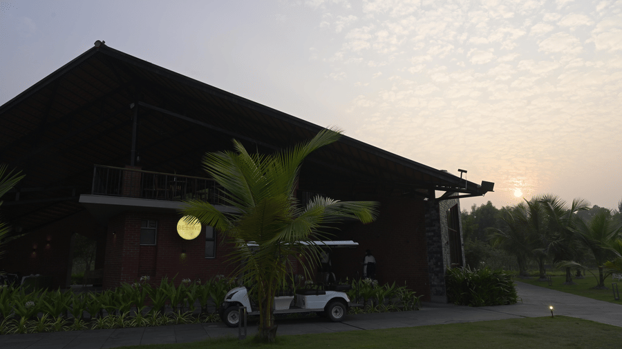 Exterior view of a large building and a white golf cart on the grass at sunset at Hotel Sonar Bangla, Sundarban.