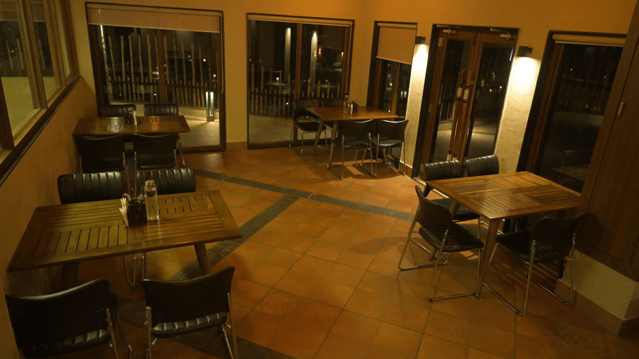 View of an indoor dining space with wooden tables and black chairs at Hotel Sonar Bangla, Sundarban.
