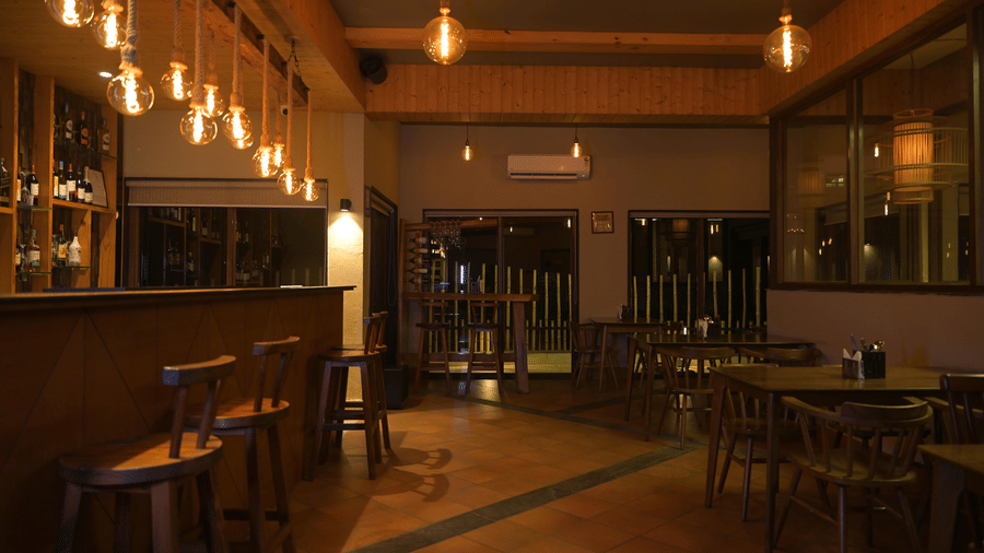 Wide shot of a bar area with wooden bar stools and warm interior lighting at Hotel Sonar Bangla, Sundarban.
