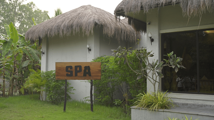 Exterior view of a spa building with a thatched roof and a wooden sign saying 'Spa', at Hotel Sonar Bangla, Sundarban.