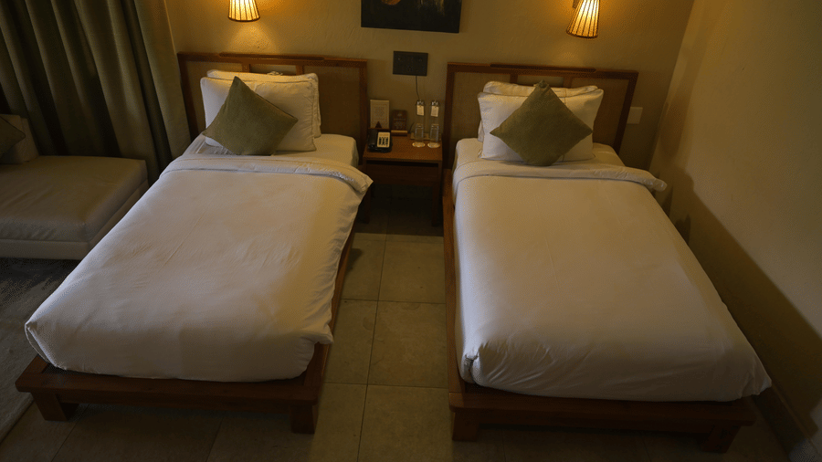 Top-down view of 2 single beds with white duvets and green accent pillows at Hotel Sonar Bangla, Sundarban.
