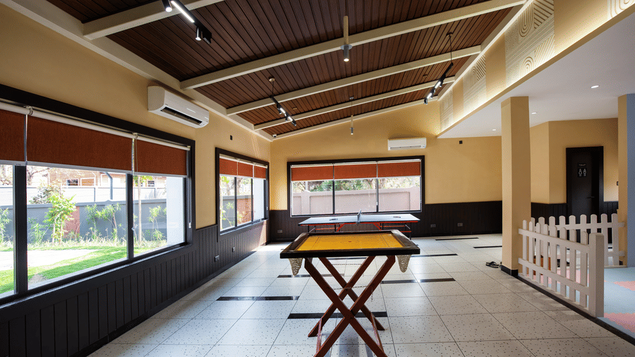 A bright indoor activity space with a table tennis setup, large open windows, and modern ceiling lighting designed for guest entertainment | Hotel Sonar Bangla, Susunia