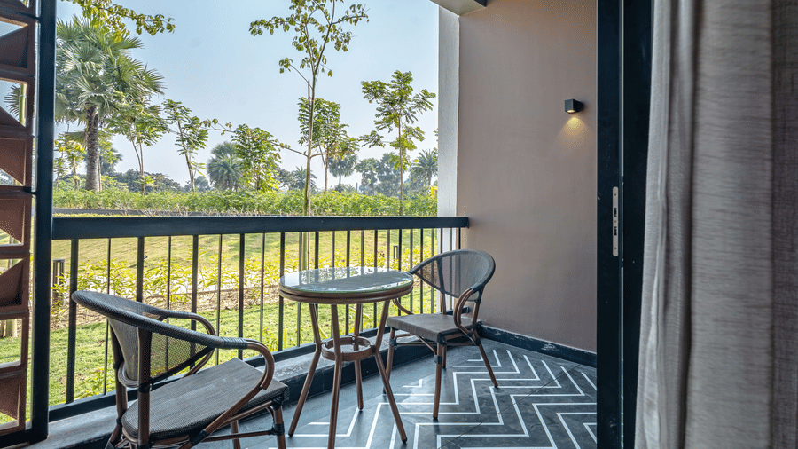 The private balcony attached to the Deluxe Room with outdoor seating overlooking lush greenery and landscaped resort surroundings | Hotel Sonar Bangla, Susunia