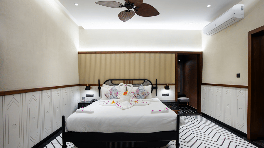 A wide-angle view of our modern hotel room in Susunia featuring a large bed, minimalist interiors, ceiling lighting, and patterned flooring design | Hotel Sonar Bangla, Susunia