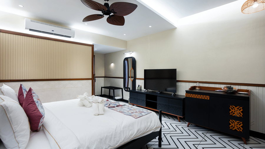A stylish suite in Susunia with a king size bed, patterned flooring, ceiling fans, and a television unit placed beside the seating area | Hotel Sonar Bangla