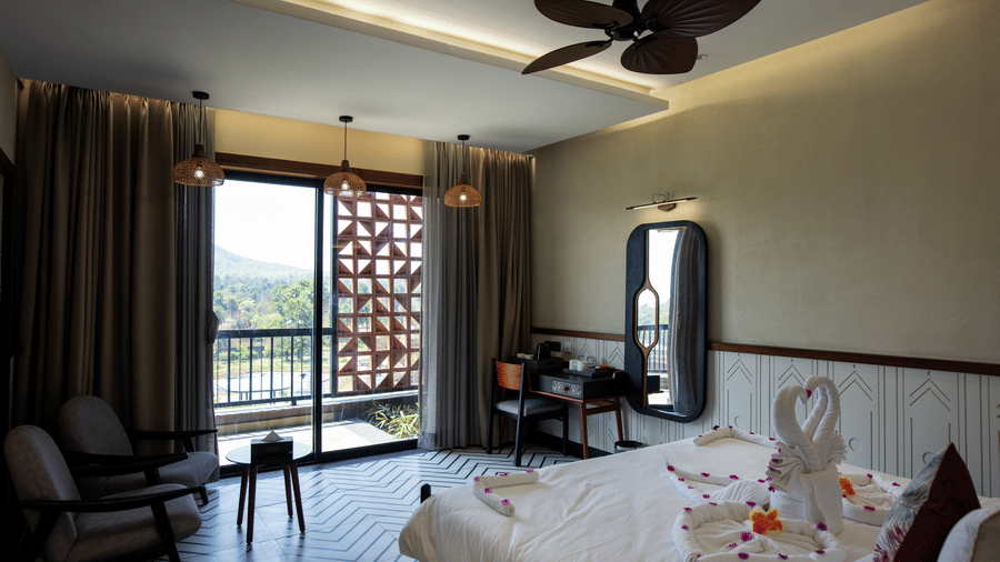 The spacious Super Deluxe Room with a large bed, elegant seating corner, balcony access, and warm ambient lighting across the interiors | Hotel Sonar Bangla, Susunia