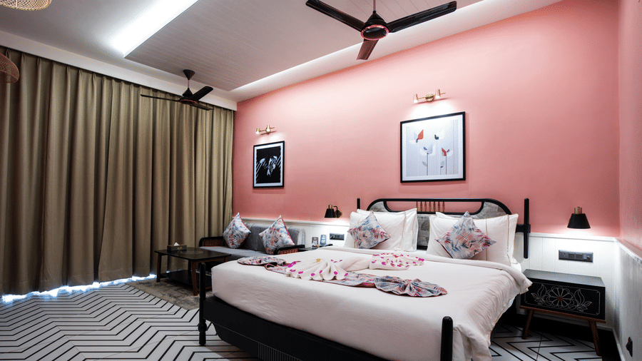 A romantic setup inside our Super Deluxe Room with decorative towel art arranged on the bed, cosy lighting, and stylish contemporary interiors | Hotel Sonar Bangla, Susunia
