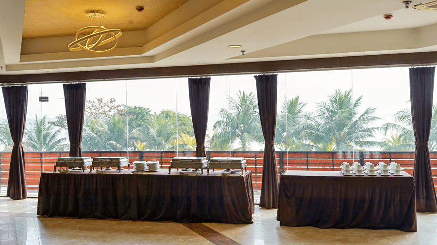 Spacious dining buffet hall with ambient ceiling lighting and brown drapes.