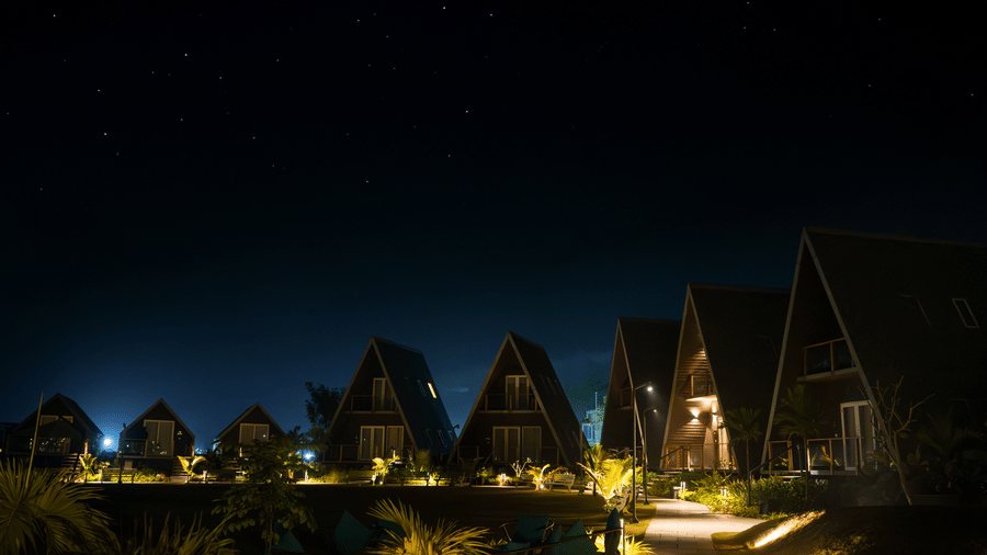 Illuminated cottage-style villa units at night with pathway lighting at Hotel Sonar Bangla, Taki.