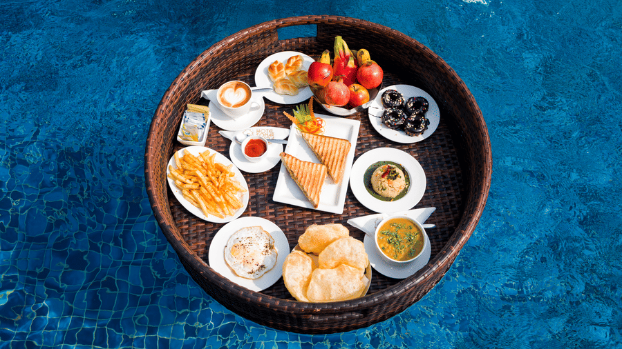 A floating food tray with snacks and fruit platter in the swimming pool at Hotel Sonar Bangla, Taki.