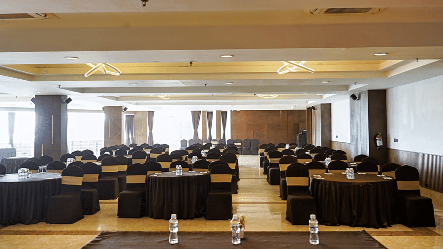Spacious banquet hall with 3 rows of chairs and tables in a theatre-style seating arrangement at Hotel Sonar Bangla,Taki.