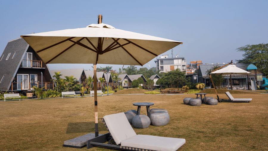 Outdoor lawn area with umbrellas at Hotel Sonar Bangla, Taki.