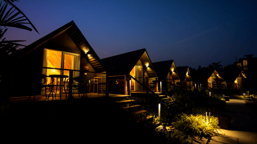 Illuminated cottage-style platinum villa units at night with pathway lighting at Hotel Sonar Bangla, Taki.