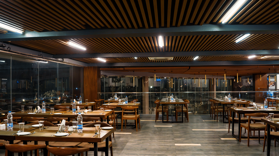 Indoor restaurant dining area with arranged tables and warm overhead lighting at Hotel Sonar Bangla, Taki.