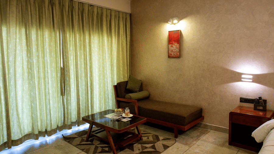 Room featurin green curtains, a small bed, table, and bedroom lights at Hotel Sonar Bangla, Taki.