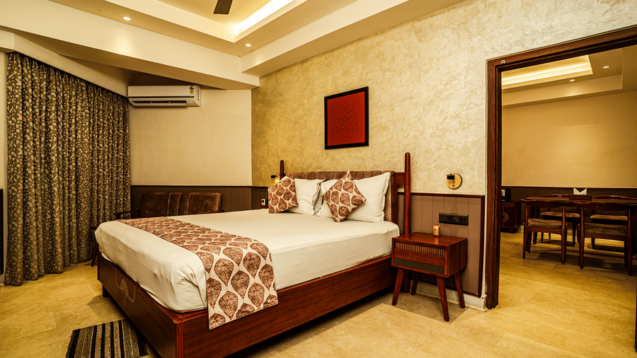The Deluxe Suite featuring a double bed, a night stand, an AC unit, and a doorway leading to the living area | Hotel Sonar Bangla, Tarapith