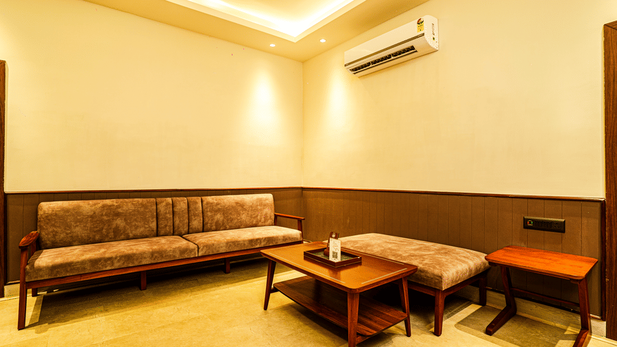 The living area of Deluxe Suite featuring a sofa, a coffee table, wooden furniture, and elegant wooden decor | Hotel Sonar Bangla, Tarapith