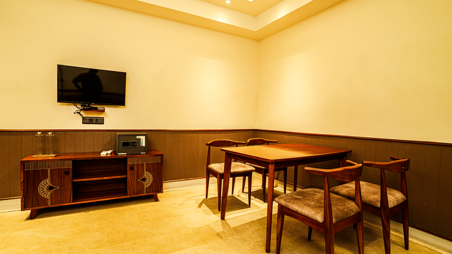 A dining table with 4 chairs, and a wall-mounted television in a corner of the living area | Hotel Sonar Bangla, Tarapith