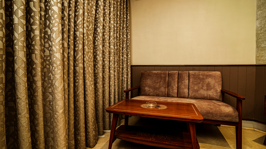 A corner of our Deluxe Suite featuring a well-cushioned sofa and a coffee table | Hotel Sonar Bangla, Tarapith