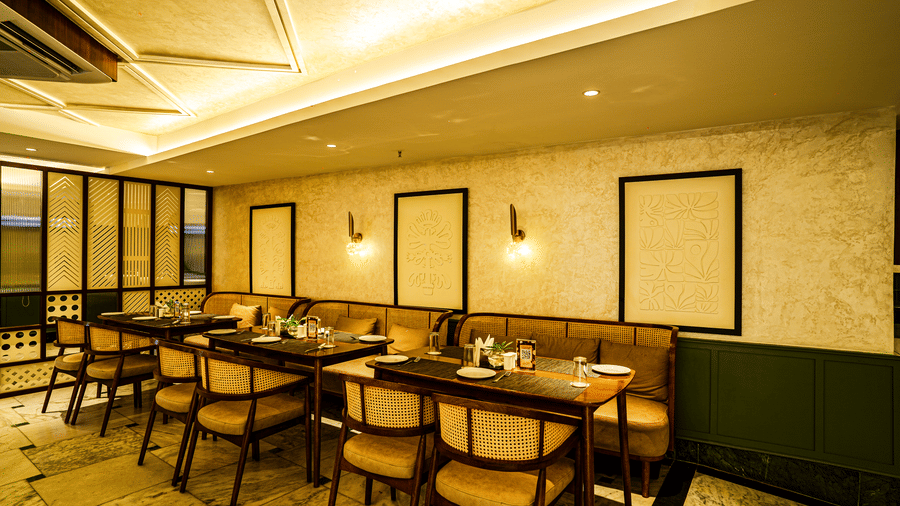 Modern dining room with symmetrical table arrangements, warm yellow lighting, and stylish interior decor | Hotel Sonar Bangla, Tarapith