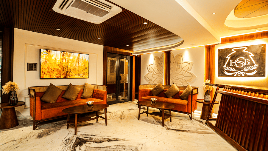The reception area featuring orange couches, coffee tables, air-conditioning, and a reception desk | Hotel Sonar Bangla, Tarapith