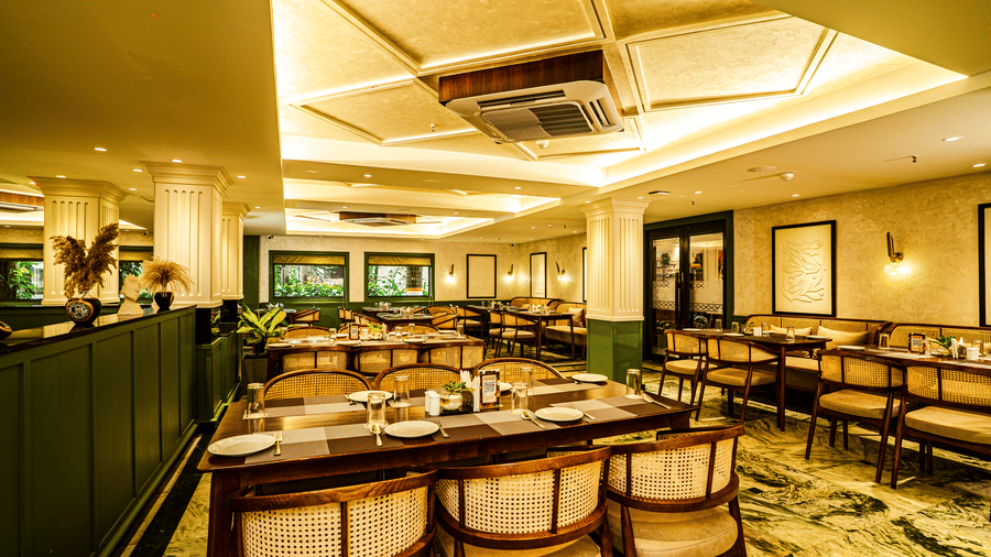 An elegant restaurant seating area with neatly arranged dining tables, warm ceiling lighting, and modern interiors | Hotel Sonar Bangla, Tarapith