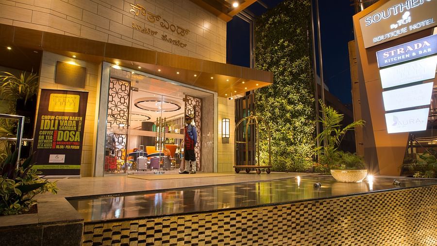 The exterior entrance of a hotel at dusk, featuring signage, a bellhop and a reflective water feature - Hotel Southend by TGI - Bommasandra, Bangalore