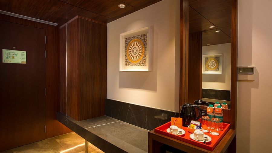 A cosy hotel nook with a bench, decorative wall art and a tea and coffee making station - Hotel Southend by TGI - Bommasandra, Bangalore