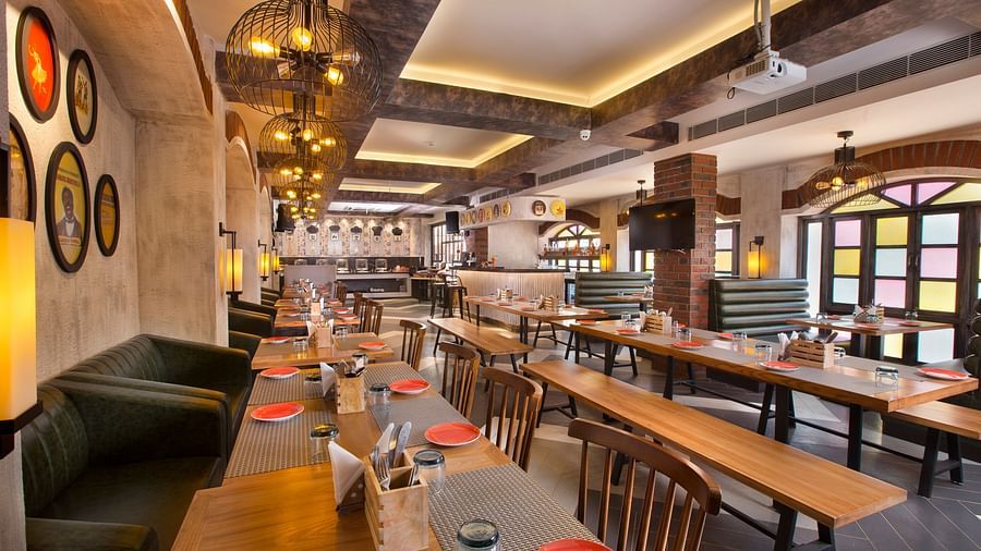 A well-lit restaurant with a mix of booth and table seating, unique lighting fixtures and decorative elements on the walls - Hotel Southend by TGI - Bommasandra, Bangalore