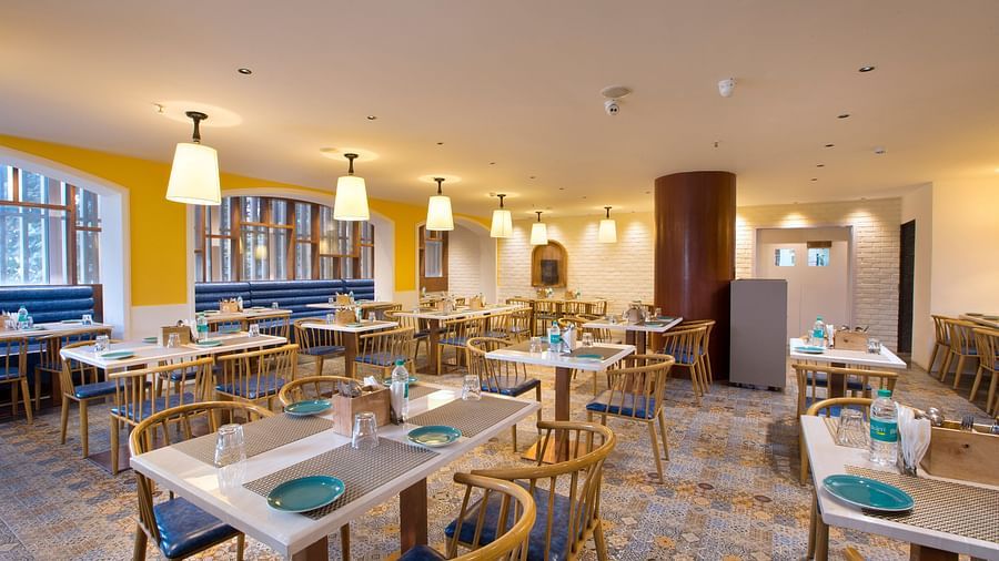 Another view of a spacious and brightly lit restaurant with wooden chairs, patterned tile floor and large windows - Hotel Southend by TGI - Bommasandra, Bangalore