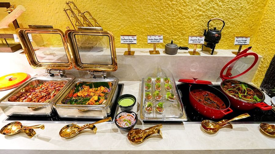 An up-close view of a buffet spread with metal serving utensils and bowls. - Tara, Comfort Hotel in Hyderabad - Ramoji Film City.