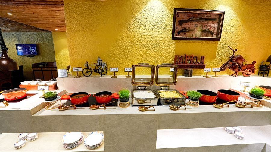 A buffet table showcasing colorful dishes and condiments under soft lighting at Tara, Comfort Hotel in Hyderabad - Ramoji Film City.
