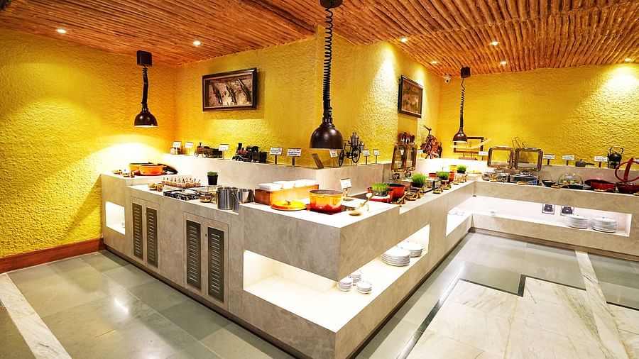 A well-arranged buffet line in a room with yellow walls and wooden ceiling at Tara, Comfort Hotel in Hyderabad - Ramoji Film City.