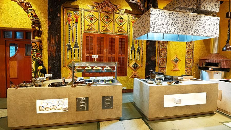 A buffet area with traditional design elements, wood carvings, and ambient lighting at Tara, Comfort Hotel in Hyderabad - Ramoji Film City.