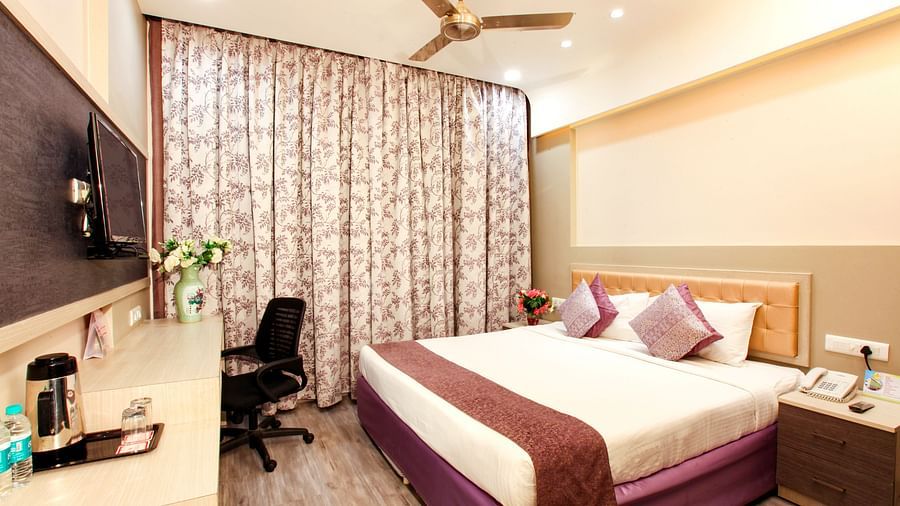 A well-appointed hotel room with a patterned headboard and modern amenities. - Tara, Comfort Hotel in Hyderabad - Ramoji Film City.