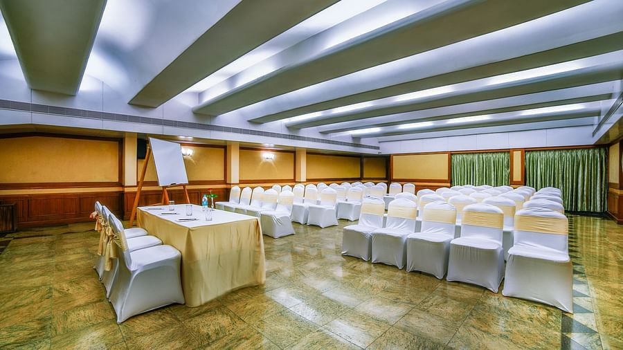 An event space in a hotel with U-shaped table setup and cream-colored chairs. - Tara, Comfort Hotel in Hyderabad - Ramoji Film City.