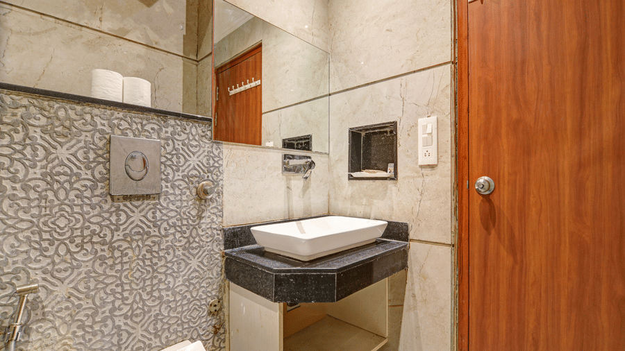 Modern bathroom vanity with a white vessel sink, large mirror, and patterned grey wall tiles - Hotel Velocity