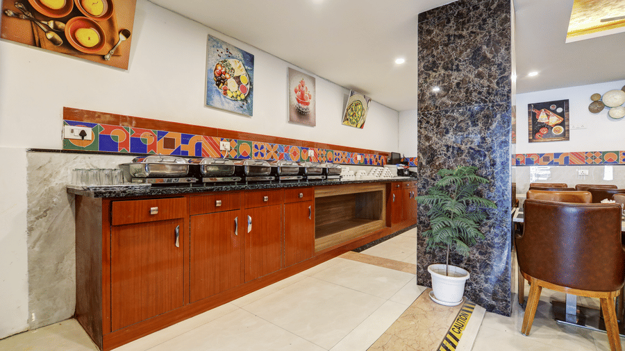 Long wooden buffet service counter with marble accents and decorative wall paintings - Hotel Velocity