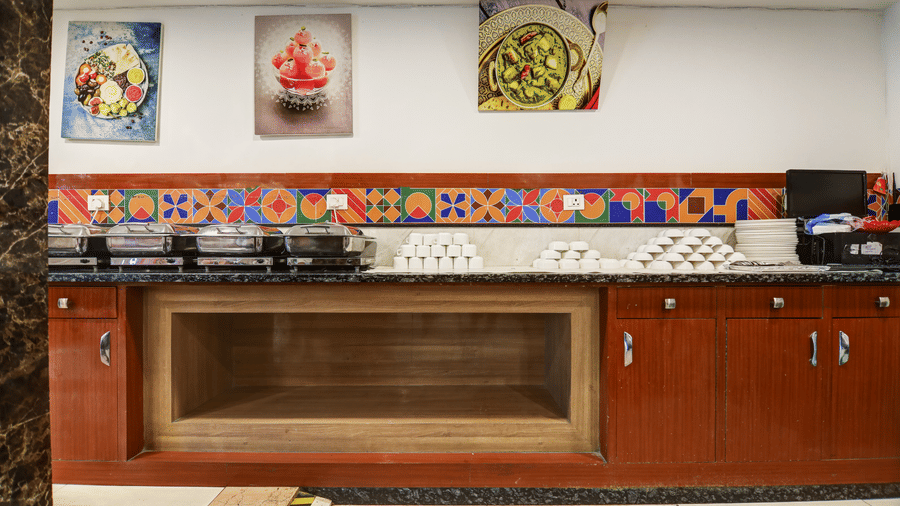 Close-up of the food service area featuring colourful wall art and clean wooden cabinetry - Hotel Velocity